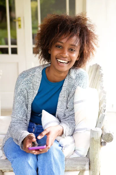 Mujer africana sonriente sentada con teléfono celular —  Fotos de Stock