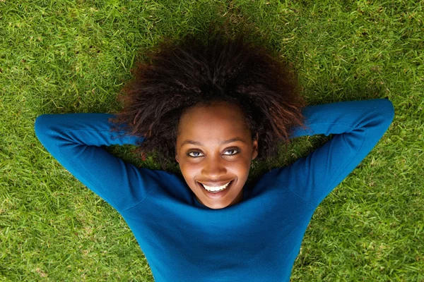 Sonriente mujer negra acostada en la hierba — Foto de Stock