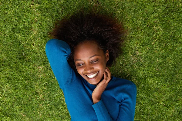 Lachende Afrikaanse vrouw liggen op gras — Stockfoto