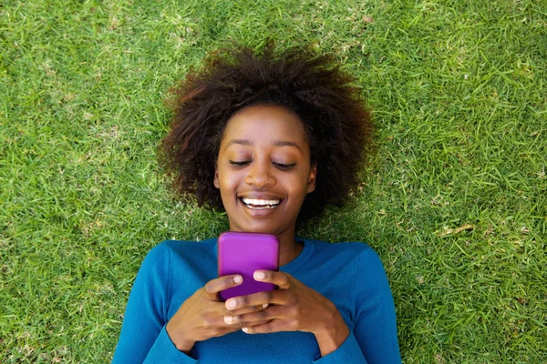 Mujer africana sonriente acostada en la hierba — Foto de Stock