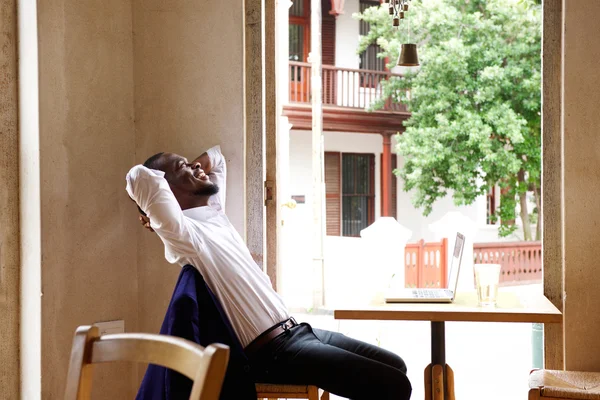 Man sitting at cafe with hands behind head — Stock Photo, Image