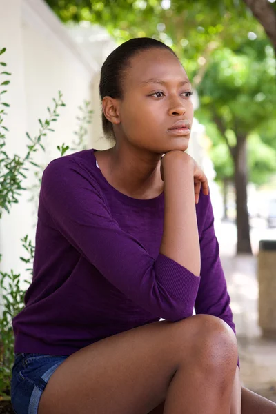 Pensive young african woman sitting alone — Stock Photo, Image