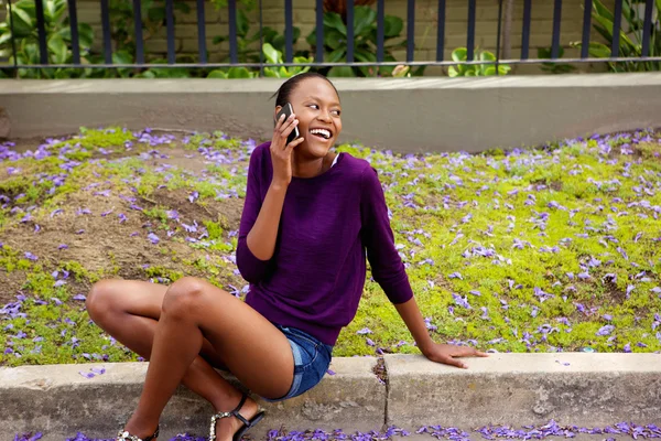 Sonriente hembra africana sentada afuera — Foto de Stock