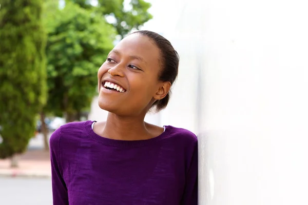 Happy young african woman leaning on wall — Stock Photo, Image