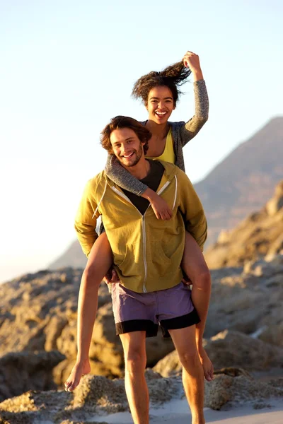 Junger Mann trägt Frau auf dem Rücken — Stockfoto
