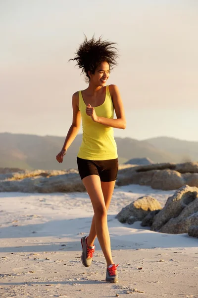 Улыбающаяся молодая женщина бежит по пляжу — стоковое фото
