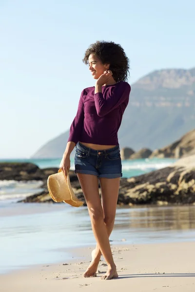 Улыбающаяся молодая женщина идет по пляжу — стоковое фото