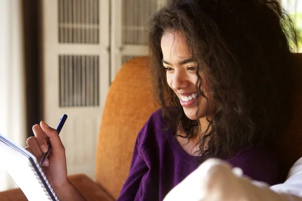 Uśmiechnięta kobieta uczeń pisze w pamiętniku — Zdjęcie stockowe
