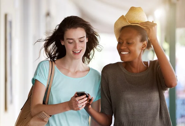 Jonge vrouwen lopen samen met behulp van mobiele telefoon — Stockfoto