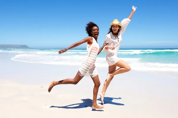 Młodzi przyjaciele, śmiejąc się i działa na plaży — Zdjęcie stockowe