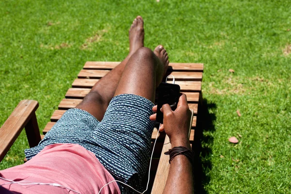 Man avkopplande på solstol med en mobiltelefon — Stockfoto