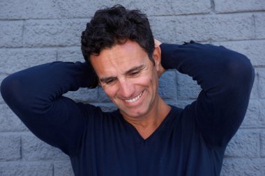 Ellerini başının arkasında ile gülümseyen olgun adam