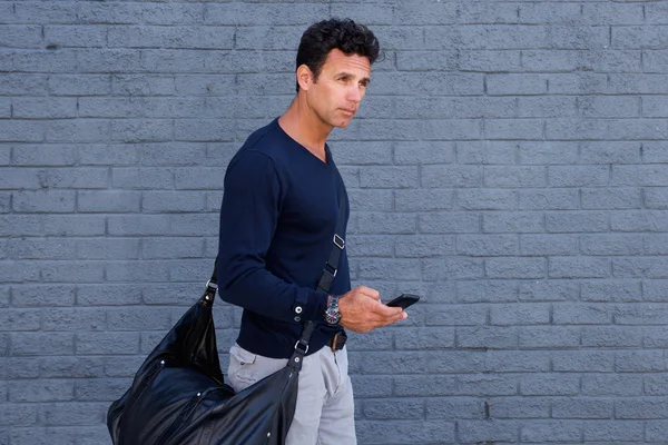 Viajante masculino caminhando com telefone celular e saco — Fotografia de Stock
