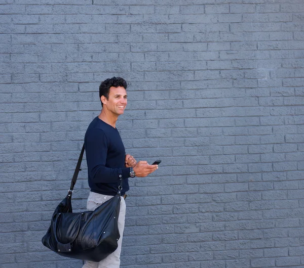 Cep telefonu ve paket ile yürüyen çekici adam