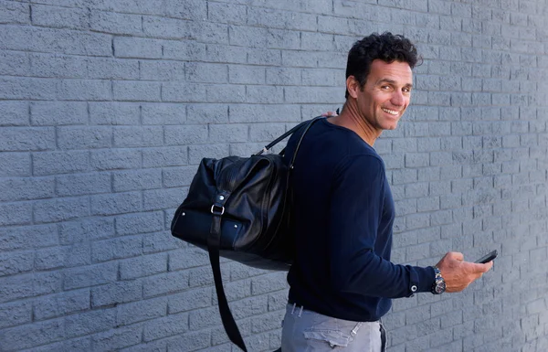 Uomo che si gira sorridendo con la borsa — Foto Stock