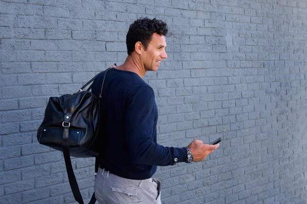 Çanta ve cep telefonu ile yürüyen adam — Stok fotoğraf
