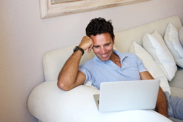 Glimlachende man om thuis te zitten met laptop — Stockfoto