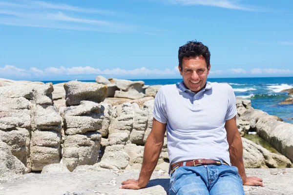 Sorridente uomo anziano seduto in spiaggia — Foto Stock