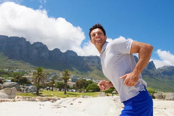 Lächelnder Mann läuft am Strand — Stockfoto