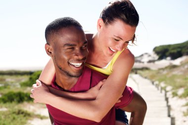 Genç adam kız arkadaşını sırtında taşıyor.