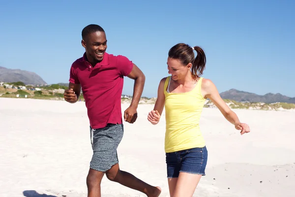 Feliz joven pareja corriendo en la playa — Foto de Stock