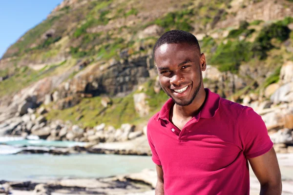 Schöner junger Mann steht am Strand — Stockfoto