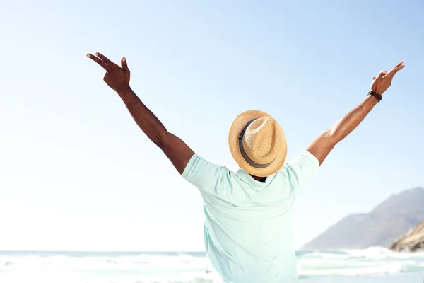 Young man standing with arms spread open at beach — Stock Photo, Image