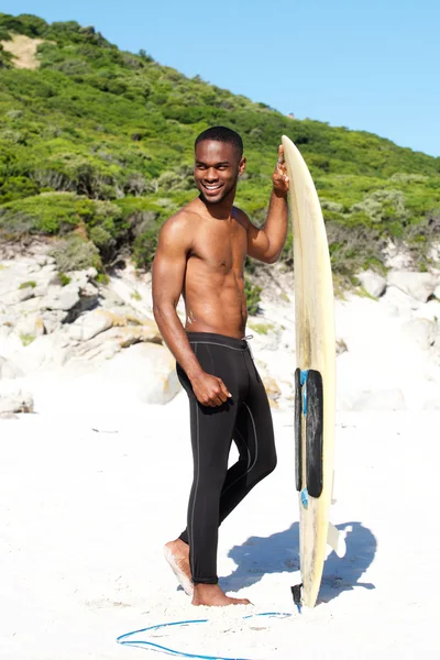 Jeune homme souriant avec planche de surf — Photo