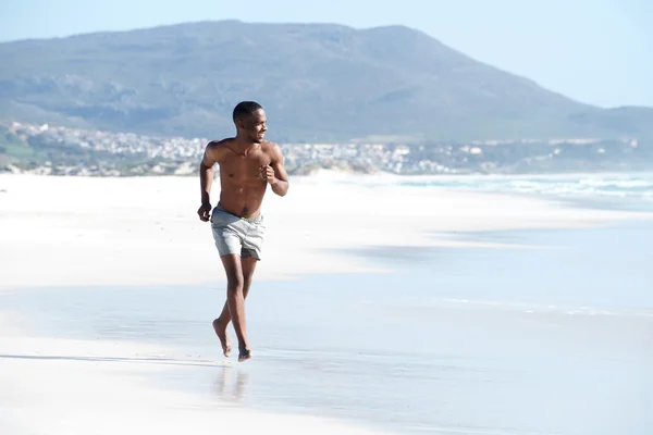 Jovem correndo ao longo da praia — Fotografia de Stock