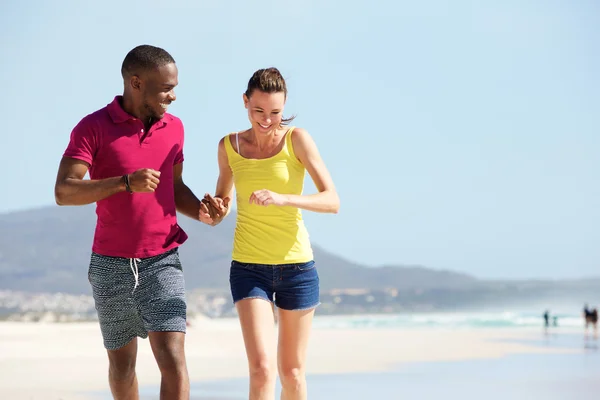 Pareja de raza mixta corriendo en la playa — Foto de Stock