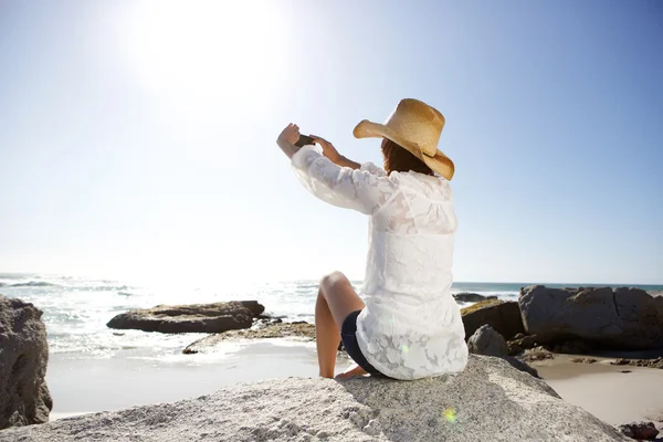 Kayanın üzerinde sahilde oturan kadın — Stok fotoğraf