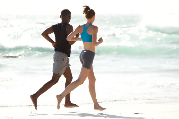 Giovane coppia che corre lungo la spiaggia — Foto Stock