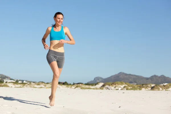 Спортивная молодая женщина бегает по пляжу — стоковое фото