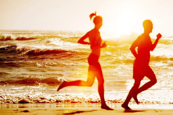Silhouette von zwei, die am Strand laufen — Stockfoto
