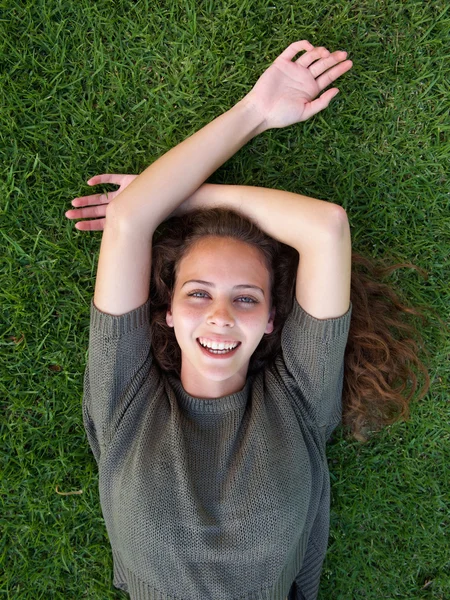 Ridere giovane donna sdraiata sull'erba — Foto Stock