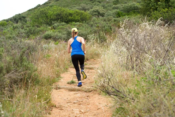 Атлетичная женщина бежит по грязной тропе снаружи — стоковое фото