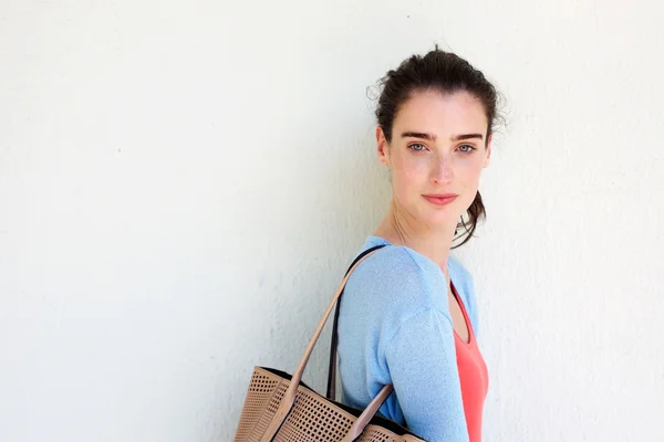 Giovane donna con borsa contro muro bianco — Foto Stock