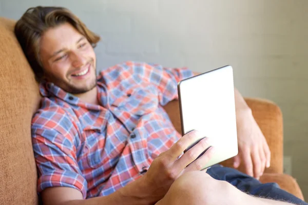 Cool mladý muž sedí na pohovce s tabletem — Stock fotografie