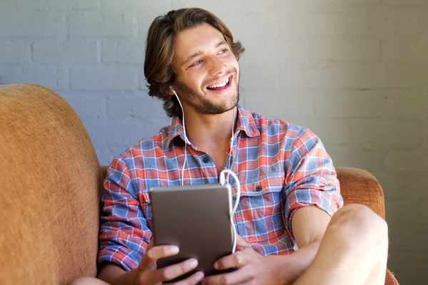 Молодой человек смеется над домом с цифровым планшетом — стоковое фото