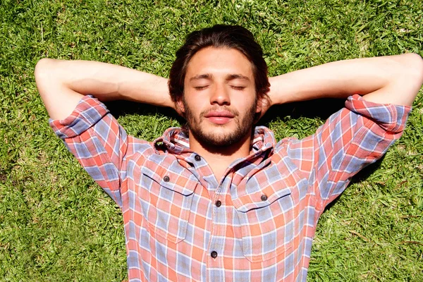 Junger Mann liegt entspannt im Gras — Stockfoto