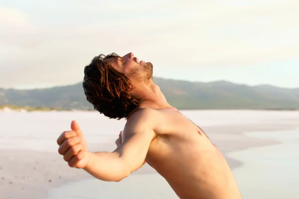Deniz kenarında eğilerek gömleksiz genç adam — Stok fotoğraf