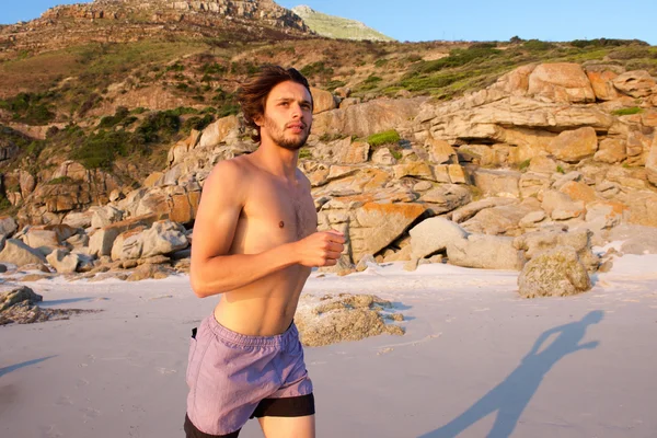 건강 한 젊은 남자가 해변에서 실행 — 스톡 사진