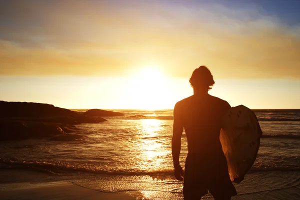 Male surfer watching the sunset at the beach — Stock Photo, Image