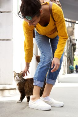 Genç kadın bir kedi ile oynarken 