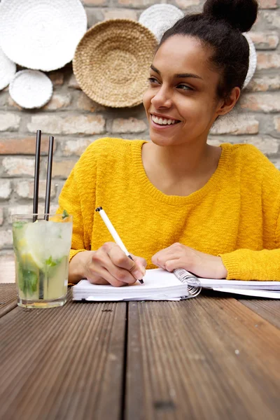 Young woman sitting at cafe and writing notes — Stock Photo, Image