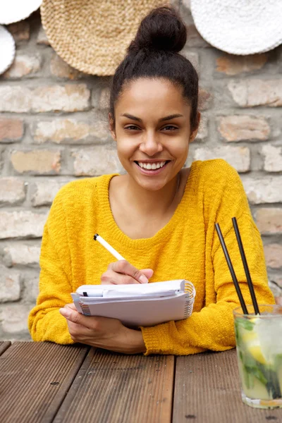 Lächelnde Frau schreibt auf Notizbuch — Stockfoto