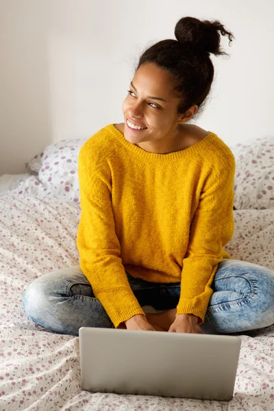 Jeune femme assise sur le lit avec ordinateur portable — Photo