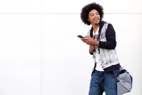 Chico joven fresco con teléfono móvil y bolsa — Foto de Stock