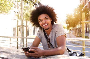 Genç adam dışında oturan cep telefonu ile gülümseyen