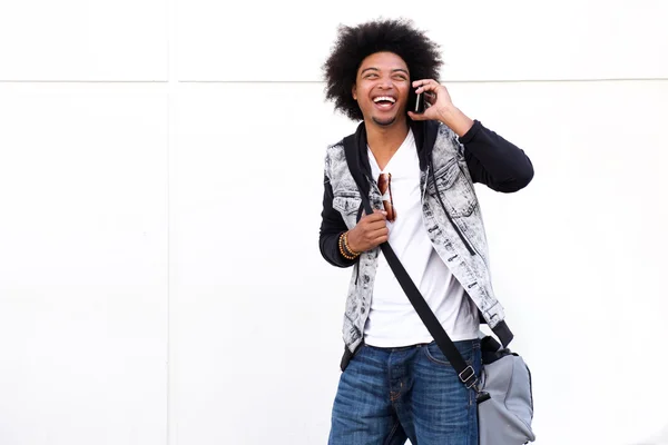 Cool black guy laughing with mobile phone and bag — Stock Photo, Image